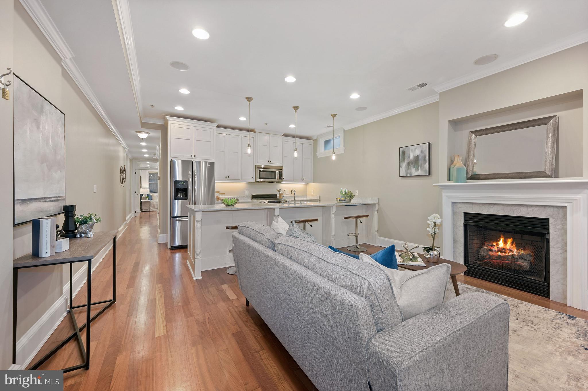 a living room with stainless steel appliances furniture a fireplace and a view of kitchen