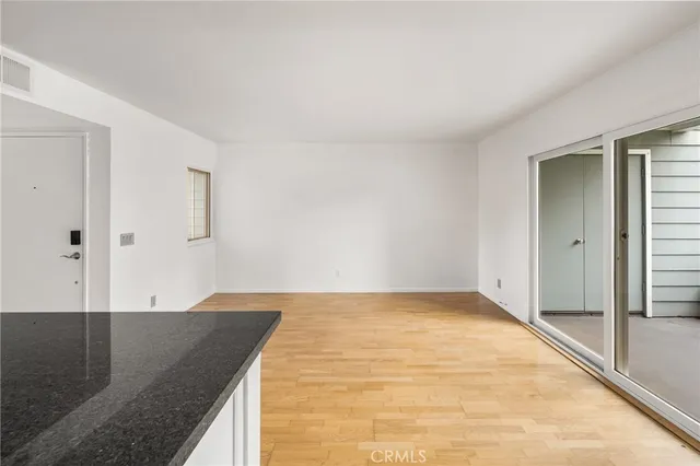a kitchen with granite countertop a stove a sink and white cabinets with wooden floor