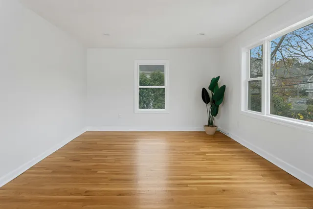 a view of an empty room with a window and wooden floor