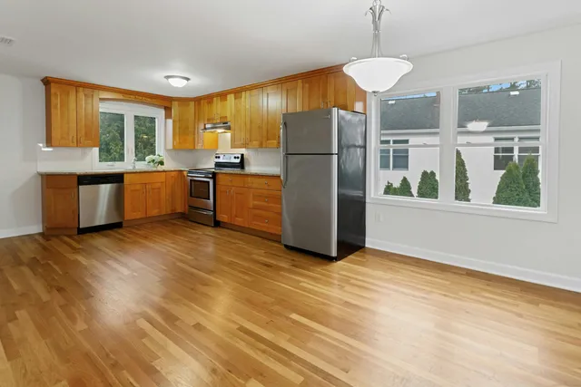 a kitchen with stainless steel appliances a refrigerator and a wooden floor