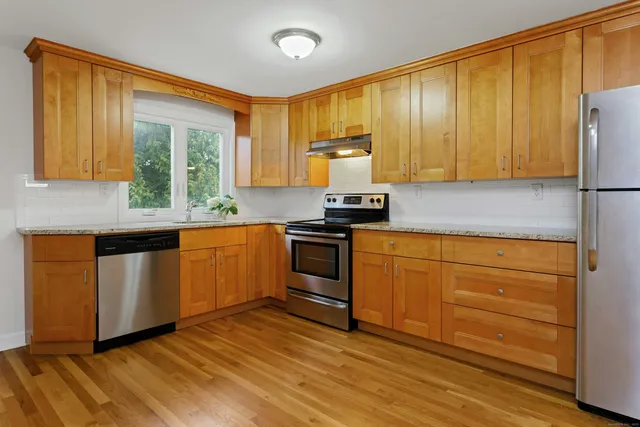 a kitchen with granite countertop wooden cabinets stainless steel appliances and a window
