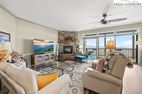 a living room with furniture a flat screen tv and a floor to ceiling window