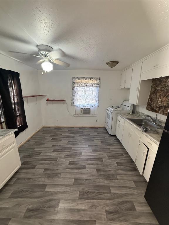 1711 Groesbeck Street Stephenville, TX 76401 - Photo 3 of 5 a kitchen with granite countertop a stove a sink and white cabinets with wooden floor