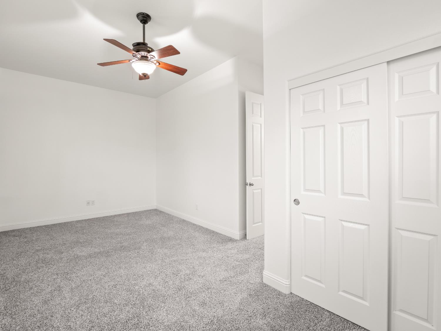 8683 North Richelle Avenue Fresno, CA 93720 - Photo 26 of 44 an empty room with a chandelier fan and wooden floor