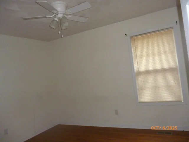 an empty room with a window and ceiling fan