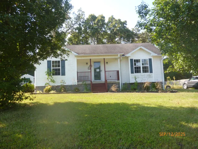 a front view of house with yard and trees in the background