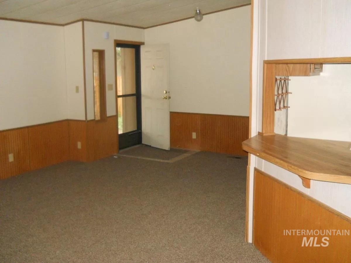 1107 East Elgin Street Caldwell, ID 83605 - Photo 5 of 5 Carpeted spare room with wood walls and a wainscoted wall