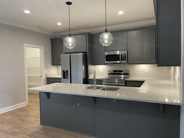 a kitchen with stainless steel appliances granite countertop a sink a stove and a refrigerator