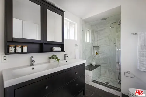 a bathroom with a double vanity sink mirror and shower