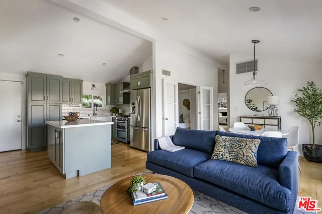 a living room with furniture kitchen and a refrigerator
