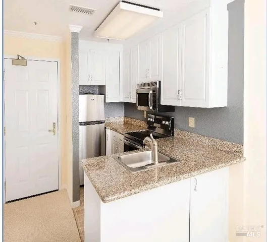 a kitchen with granite countertop a sink a refrigerator and a stove