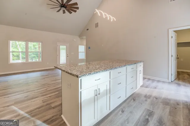 a hall with kitchen island white cabinets and wooden floor
