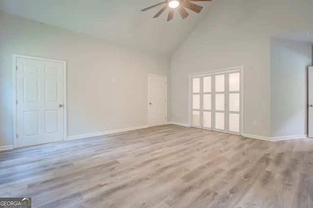 a view of an empty room with a window and wooden floor