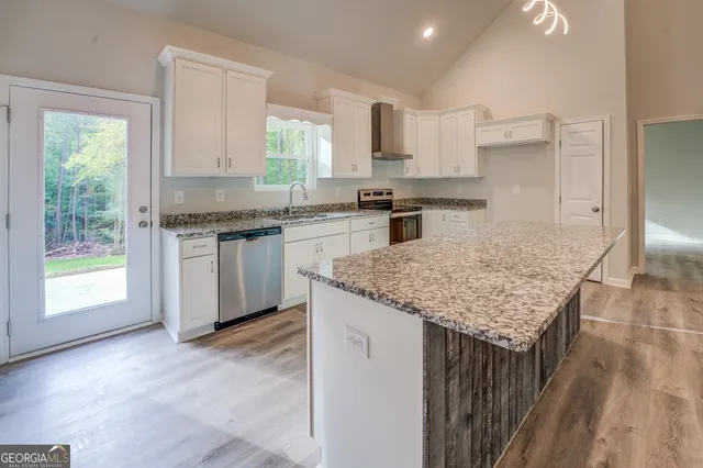 a kitchen with granite countertop kitchen island a sink stove and cabinets