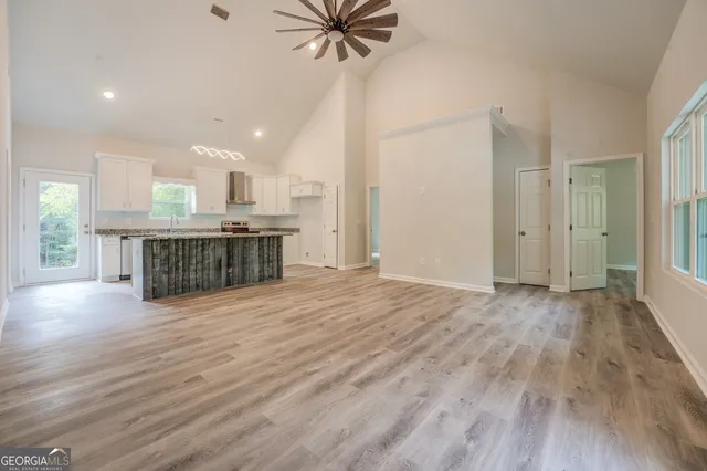 an empty room with wooden floor fireplace and windows