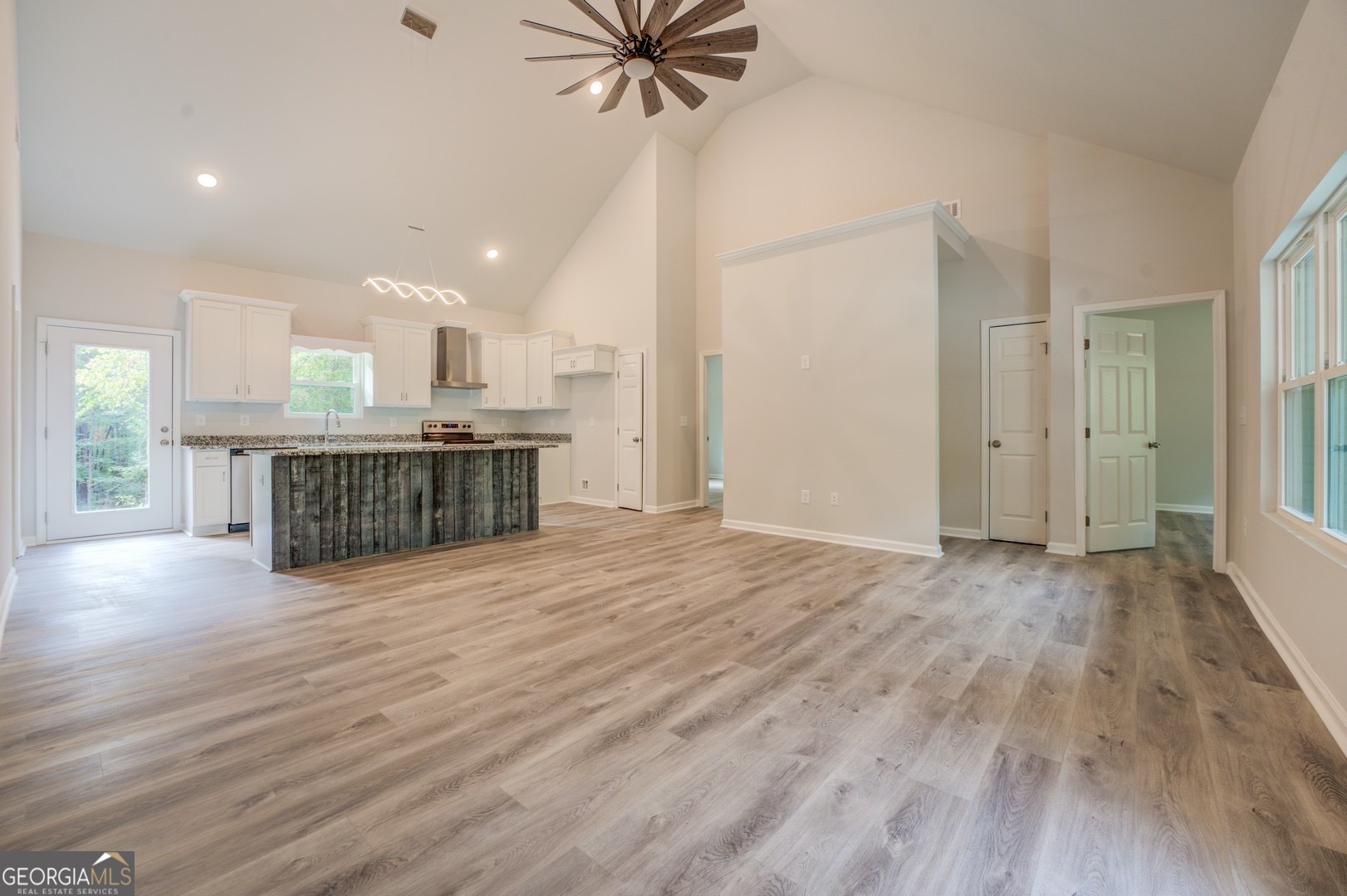 359 Whippoorwill Road Monticello, GA 31064 - Photo 9 of 37 an empty room with wooden floor fireplace and windows