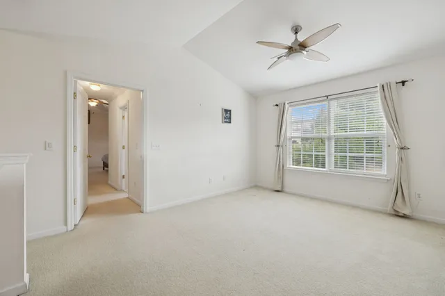 an empty room with chandelier fan and windows