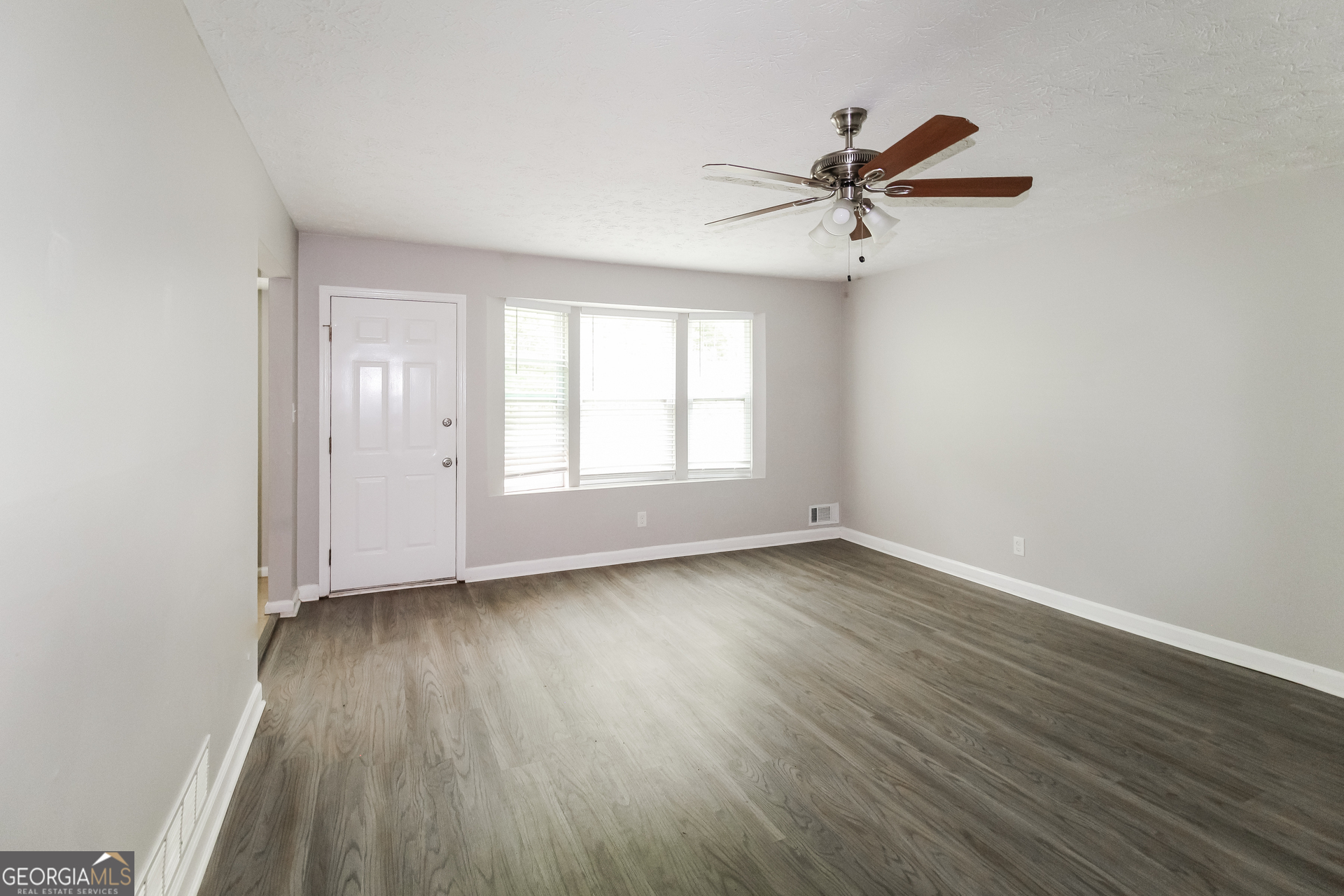 858 Martin Road Stone Mountain, GA 30088 - Photo 4 of 15 an empty room with wooden floor a ceiling fan and windows