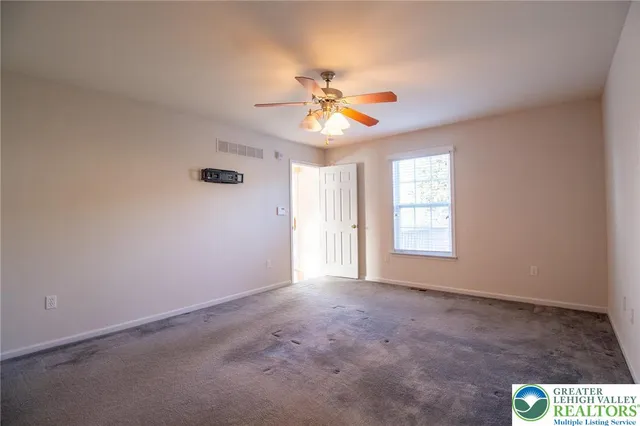 an empty room with windows and fan