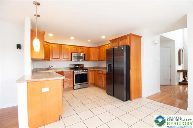 a kitchen with stainless steel appliances granite countertop a refrigerator a stove and a sink