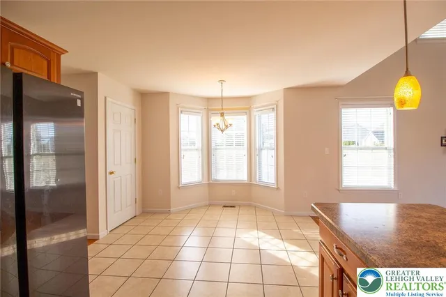 a view of an empty room with window and chandelier fan
