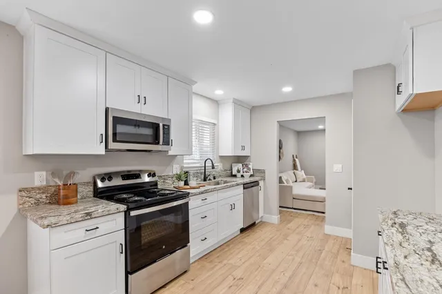 a kitchen with stainless steel appliances a white stove top oven and white cabinets