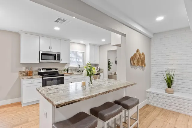 a kitchen with granite countertop kitchen island white cabinets and stainless steel appliances