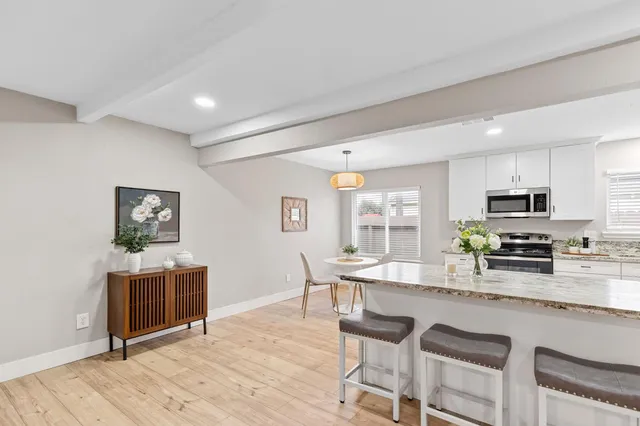 a kitchen with stainless steel appliances a kitchen island hardwood floor sink stove dining table and chairs