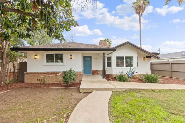 a front view of a house with a yard and potted plants