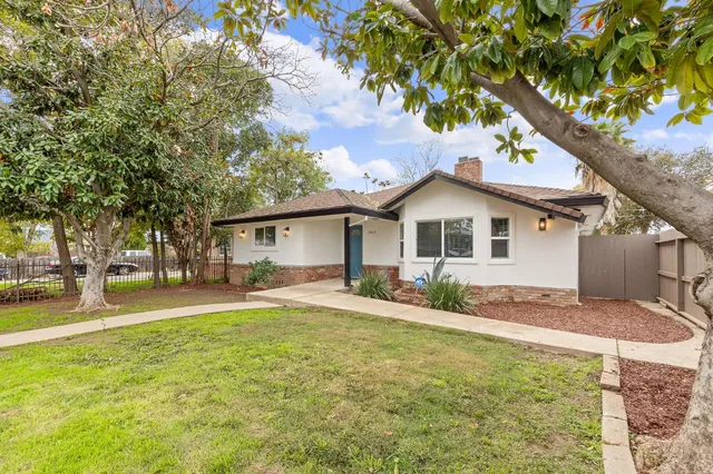 a view of a yard in front of a house with large trees