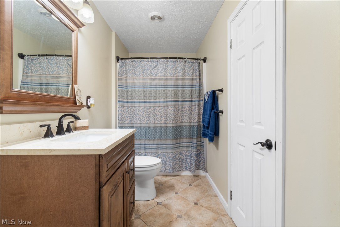 3255 Old Weymouth Road Medina, OH 44256 - Photo 21 of 31 Bathroom featuring tile flooring, vanity, toilet, and a textured ceiling