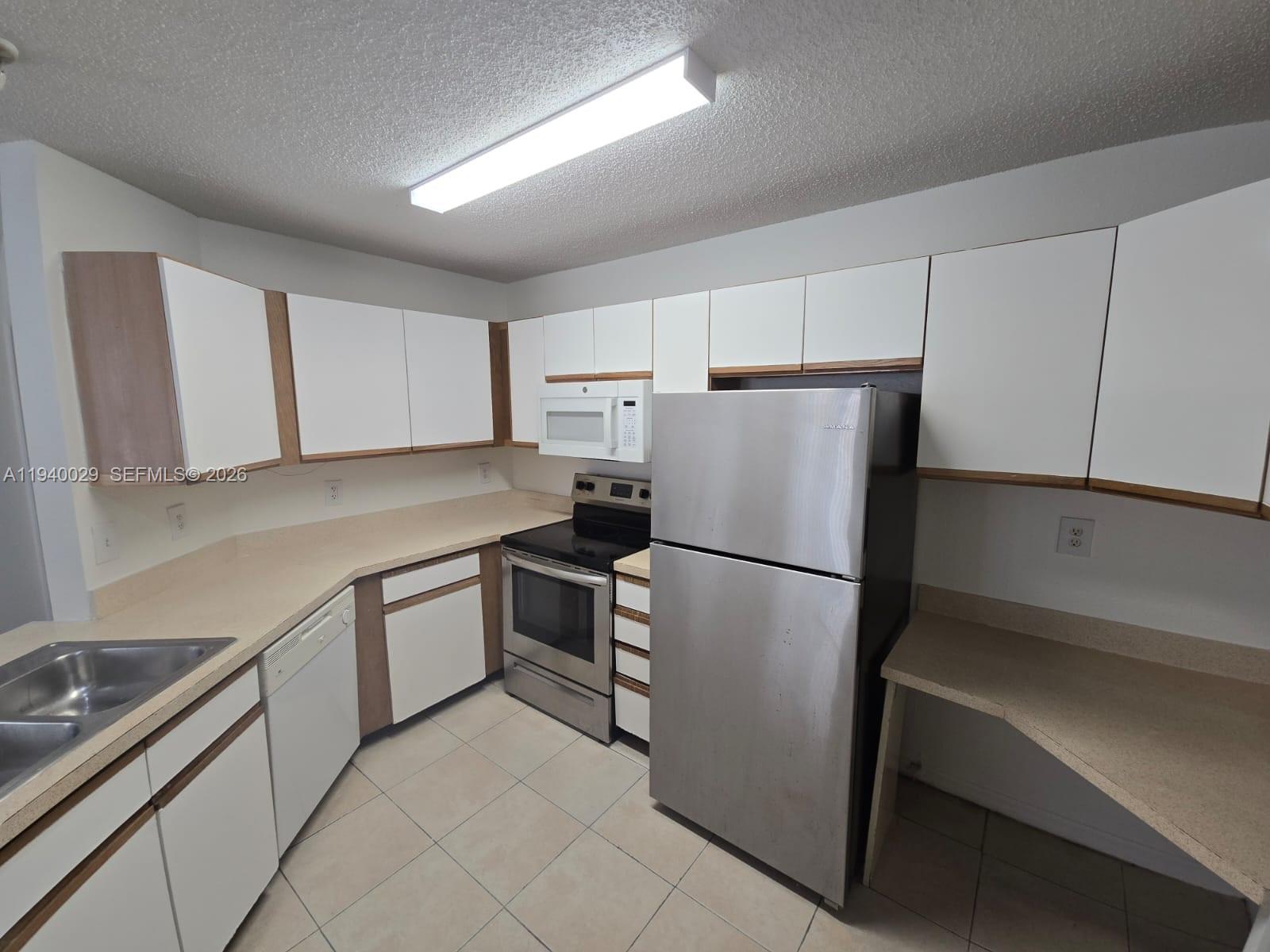 4035 West McNab Road, Unit F210 Pompano Beach, FL 33069 - Photo 12 of 22 a white refrigerator freezer sitting in a kitchen