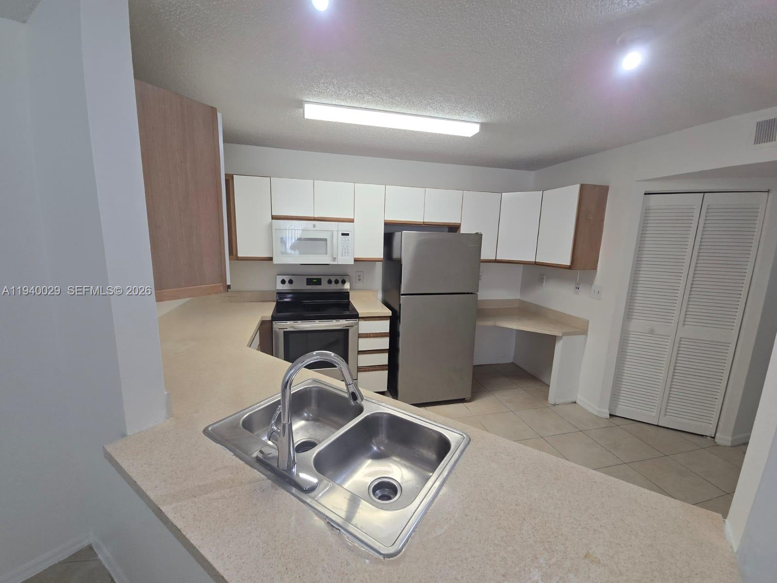 4035 West McNab Road, Unit F210 Pompano Beach, FL 33069 - Photo 10 of 22 a kitchen with a refrigerator a stove a sink and a cabinets
