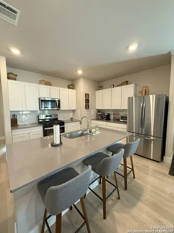 a kitchen with stainless steel appliances granite countertop a refrigerator a stove a sink a dining table and chairs