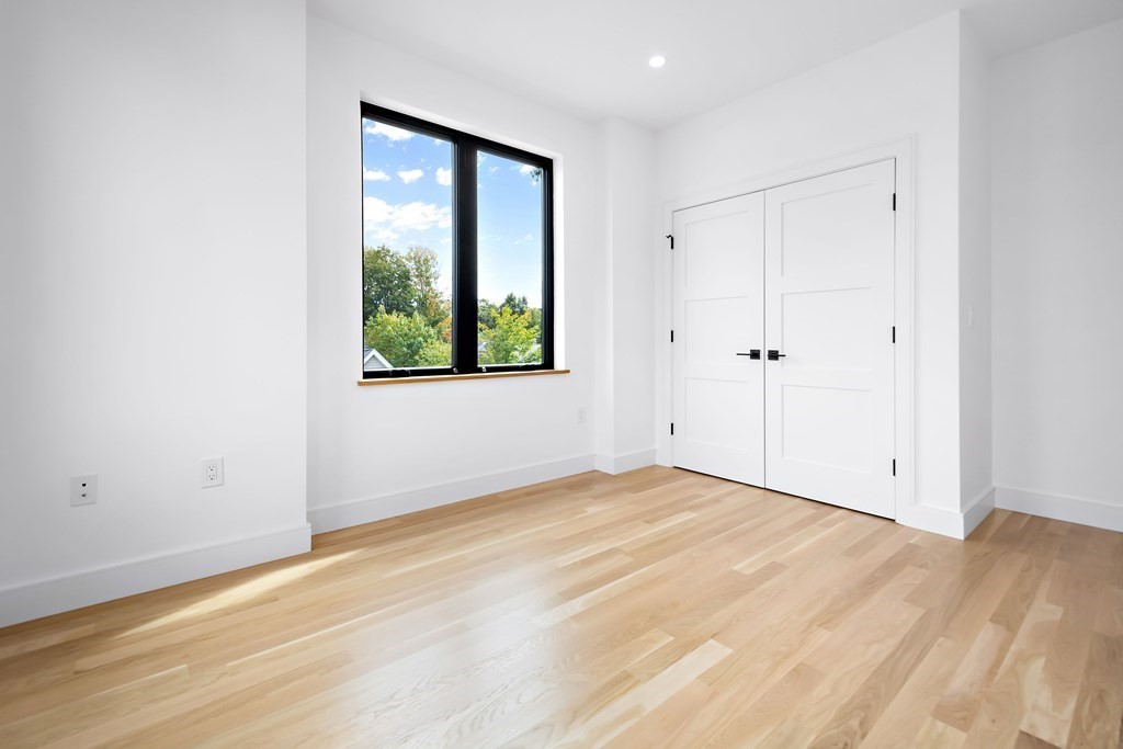 25 Tolman Street, Unit 1 Waltham, MA 02453 - Photo 17 of 36 a view of an empty room with wooden floor and a window