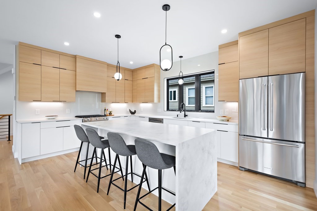 25 Tolman Street, Unit 1 Waltham, MA 02453 - Photo 5 of 36 a kitchen with stainless steel appliances a dining table chairs refrigerator and sink