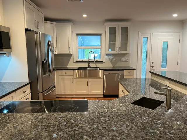 a kitchen with stainless steel appliances granite countertop a sink a stove and a refrigerator