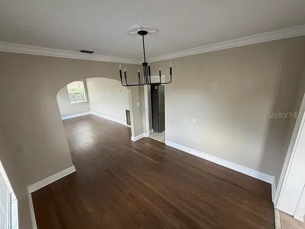 a view of a hallway with wooden floor and chandelier