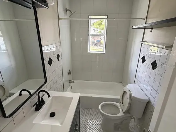 a bathroom with a sink a mirror a tub and shower