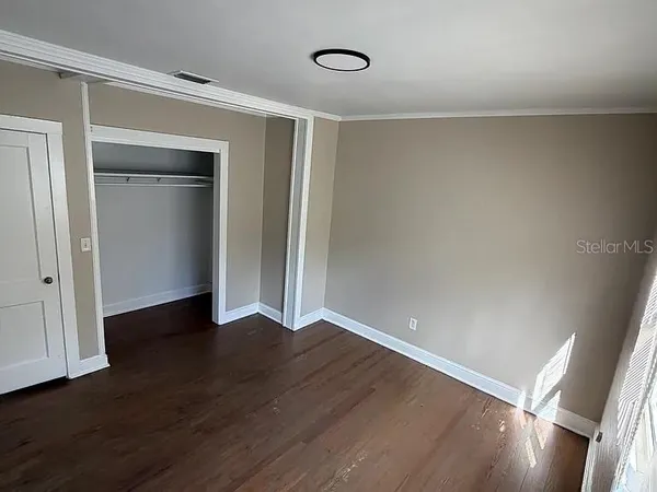 a view of an empty room with wooden floor and a window