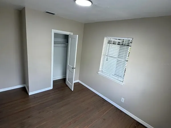 a view of an empty room with wooden floor and a window