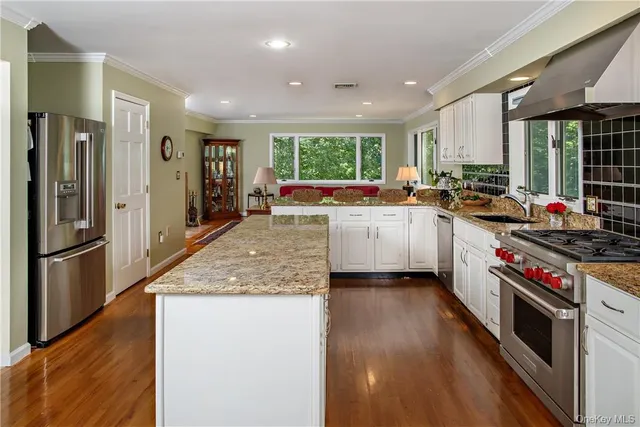 a large kitchen with stainless steel appliances granite countertop a large stove a sink dishwasher and a refrigerator with wooden floor