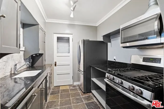 a kitchen with granite countertop a sink stove and refrigerator