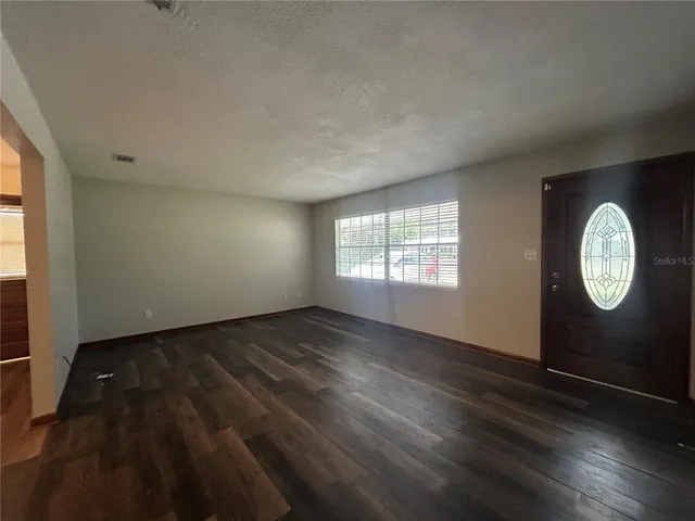 an empty room with wooden floor and windows