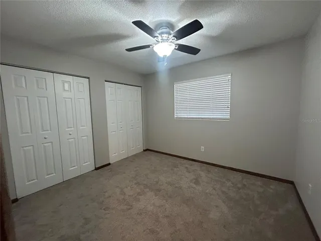 an empty room with ceiling fan and window