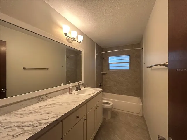 a bathroom with a granite countertop sink a large mirror a bathtub and shower