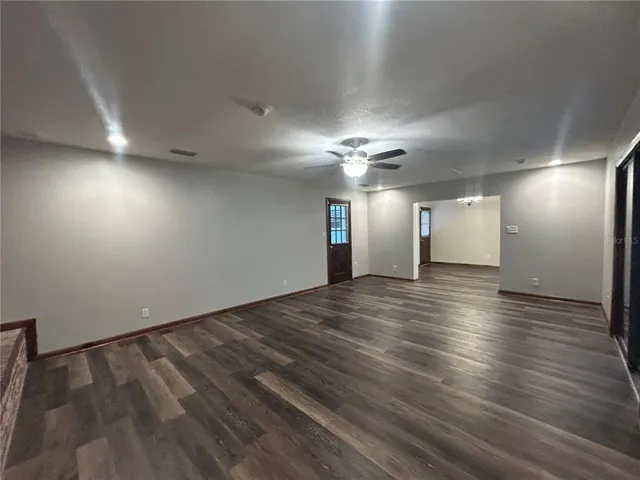 an empty room with wooden floor and chandelier