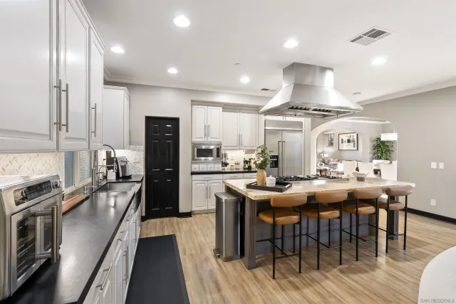 a kitchen with stainless steel appliances a dining table chairs stove refrigerator and cabinets