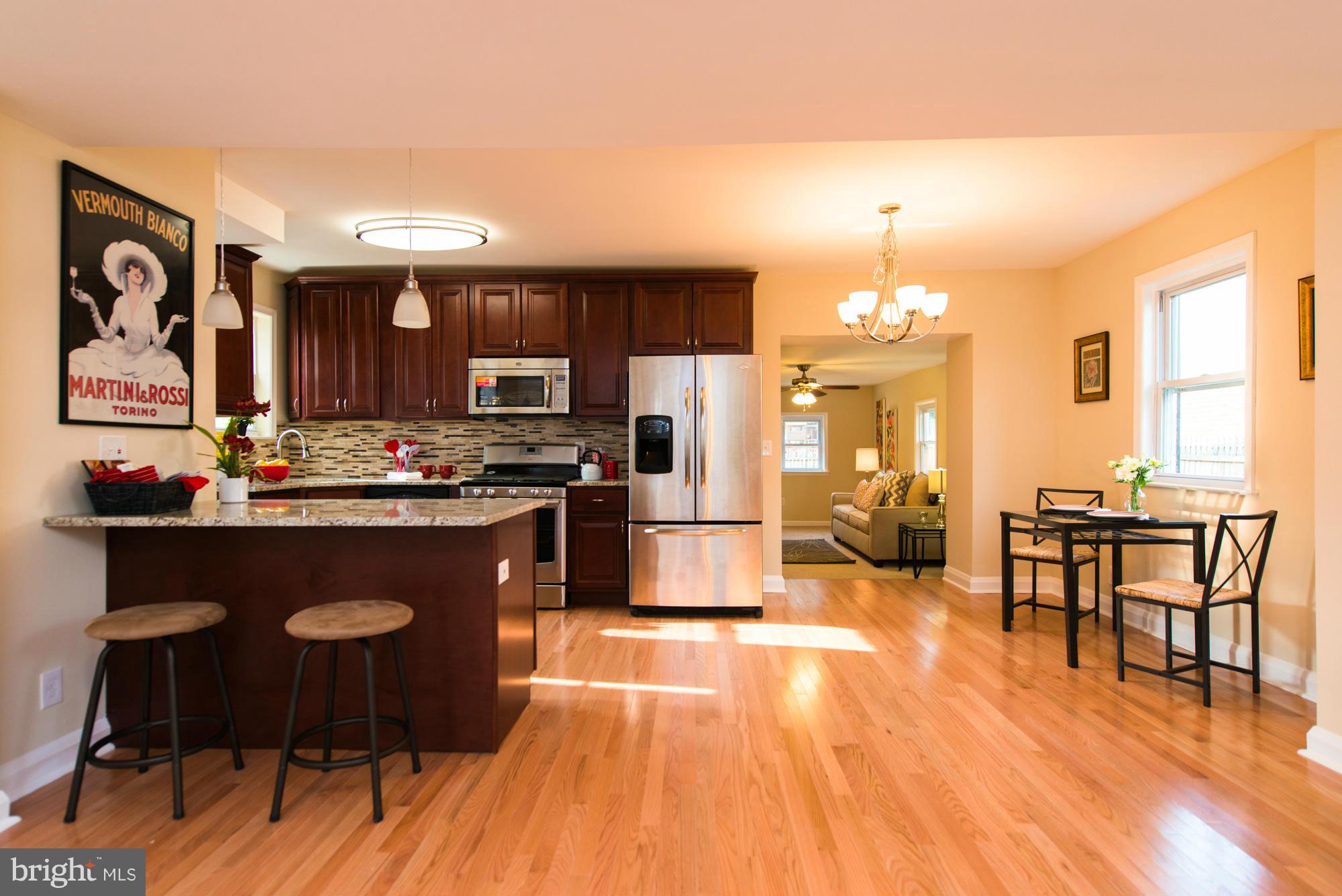 6812 Dunhill Road Baltimore, MD 21222 - Photo 7 of 30 a kitchen with stainless steel appliances granite countertop a stove top oven a refrigerator a dining table and chairs with wooden floor