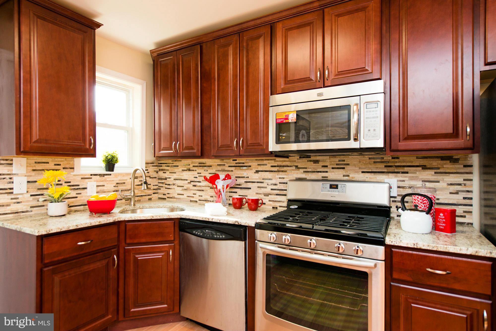 6812 Dunhill Road Baltimore, MD 21222 - Photo 9 of 30 a kitchen with stainless steel appliances granite countertop wooden cabinets and a stove top oven